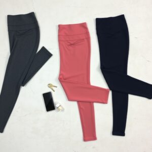 workout leggings review — Three pairs of high-rise workout leggings in charcoal, dusty rose, and navy flat-laid on concrete with a phone and key nearby.