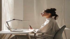 phone stand neck strain — Person at desk with phone on ergonomic stand positioned at eye level, demonstrating proper neck alignment.