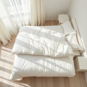 winter duvet sets — A plush white comforter on a neatly made bed in a bright Scandinavian-style bedroom with morning sunlight